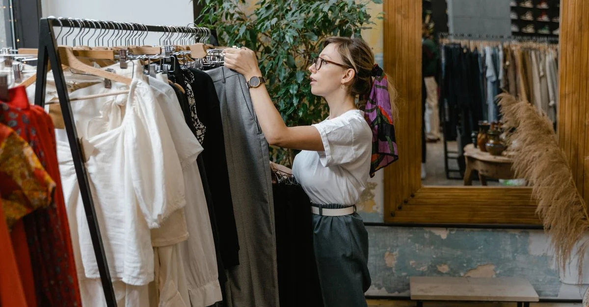 Une femme élégante regardant des vêtements dans une boutique de mode moderne avec une décoration en bois.