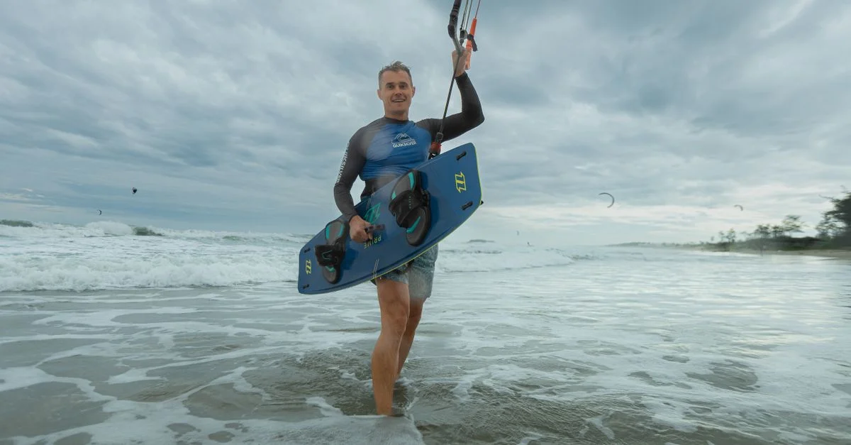 Homme faisant du kitesurf par une journée nuageuse, appréciant les vagues de l'océan et l'aventure aquatique.