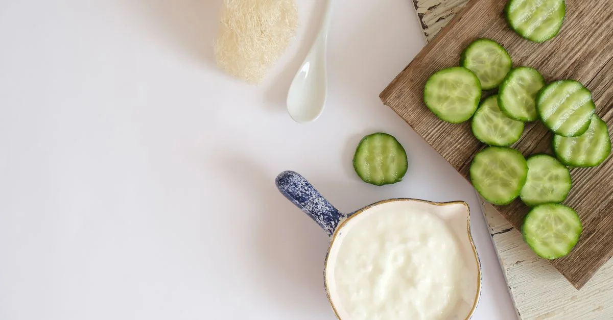 Vue plongeante de tranches de concombre frais et de yaourt crémeux sur une planche en bois rustique, idéal pour des concepts d'alimentation saine.