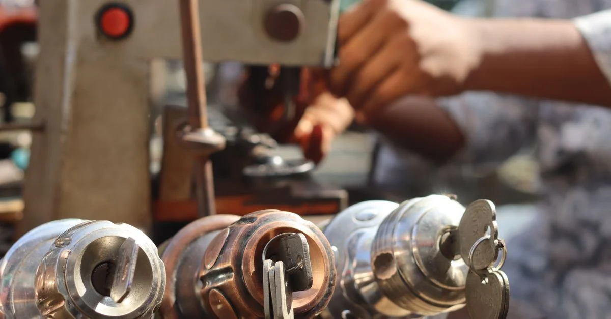 Gros plan sur des outils de serrurier et des mains travaillant avec une machine à clés en extérieur.