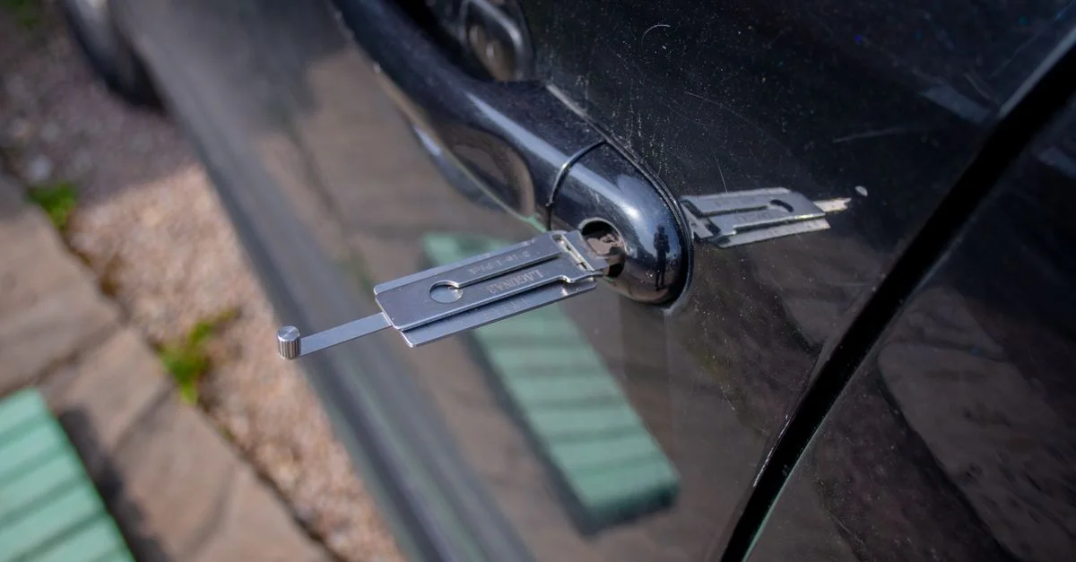 Gros plan sur un outil de serrurier inséré dans une serrure de voiture, démontrant l'accès à la sécurité.
