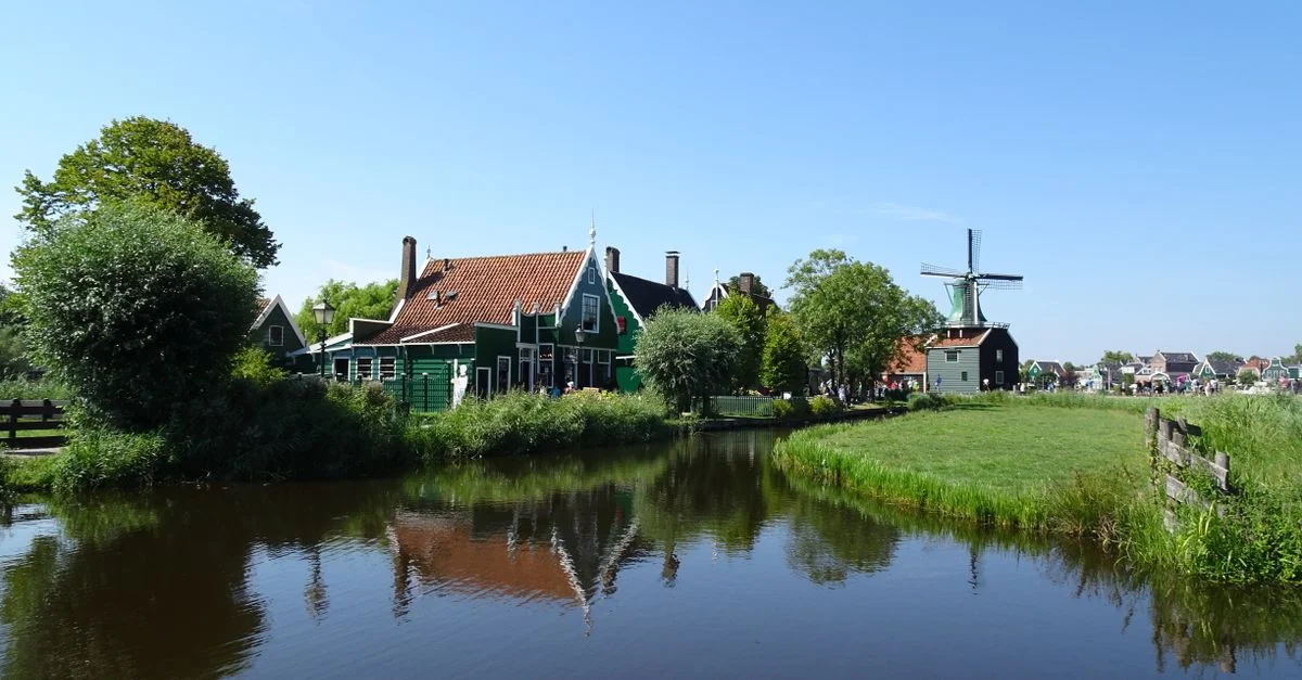 Scène idyllique d'un village néerlandais traditionnel avec moulin à vent et canal à Zaandam.