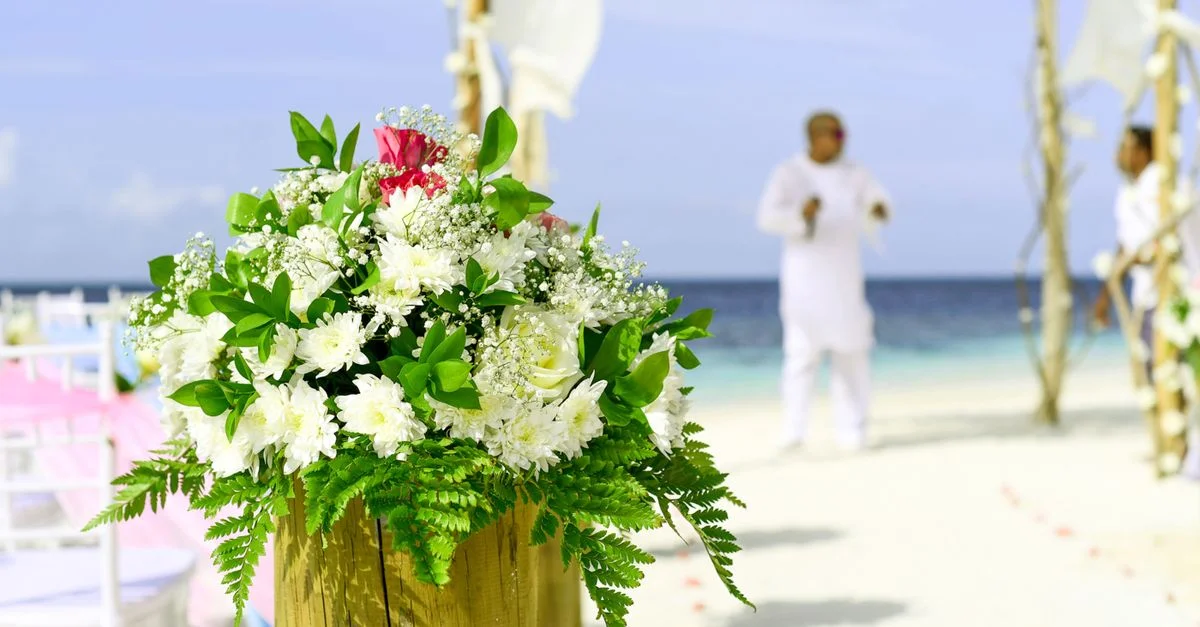 Élégante configuration de mariage sur la plage avec une décoration florale vibrante et une vue sur l'océan.