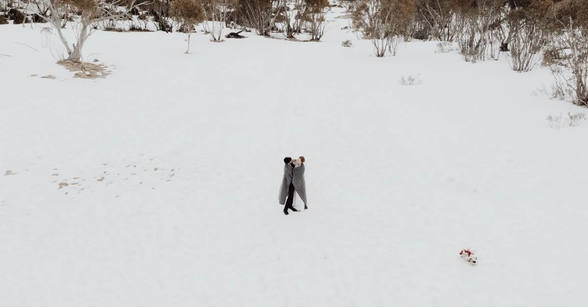 Un couple romantique s'embrassant dans un paysage enneigé, symbolisant l'amour et l'intimité.