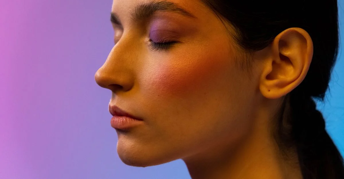 Vue latérale en gros plan d'une femme avec un fard à joues vibrant et un maquillage des yeux dans un cadre de studio.