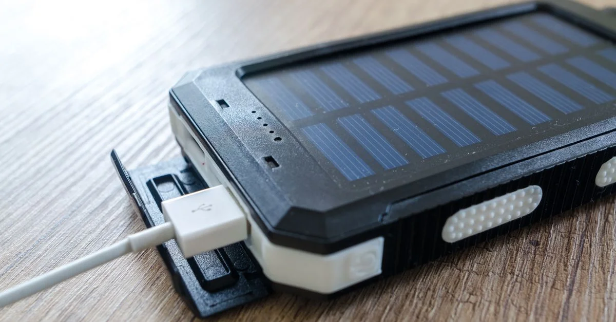 Gros plan sur un chargeur solaire avec connexion USB sur une surface en bois, mettant en avant la technologie moderne.