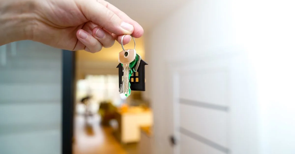 Une main tenant les clés de la maison à l'intérieur d'un appartement moderne, symbolisant une nouvelle propriété ou une location.