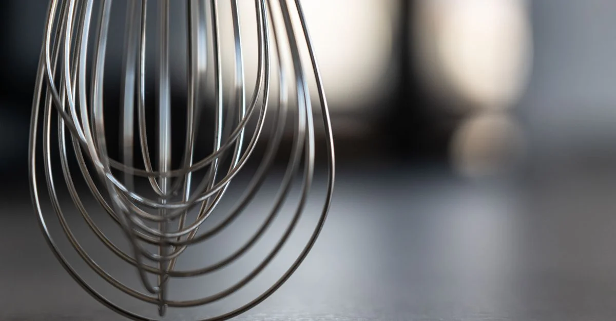 Gros plan d'un fouet en acier inoxydable dans un cadre de cuisine moderne, mettant en valeur un design élégant.