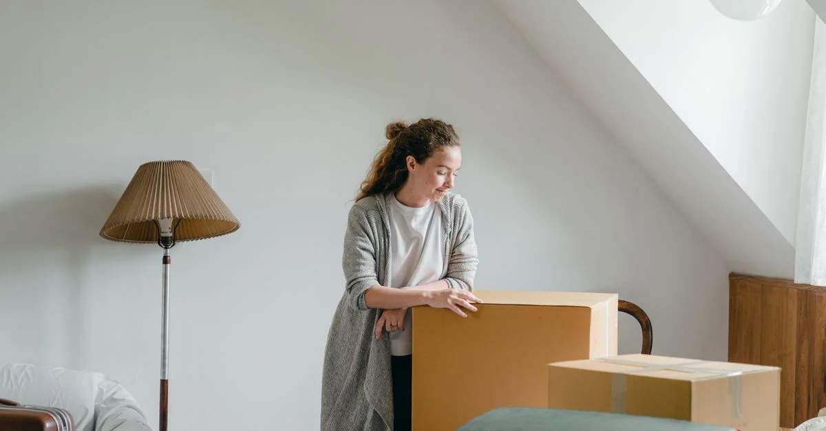Femme dans un cadre calme, réfléchissant à un déménagement avec des cartons dans une pièce sous les combles.