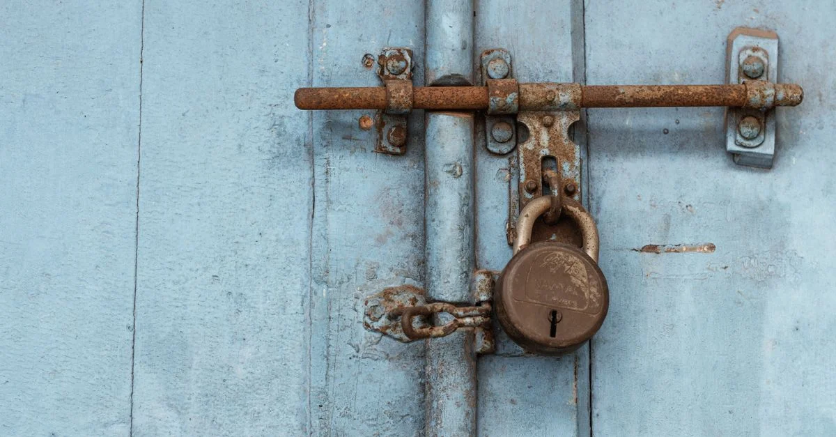 Gros plan sur un vieux cadenas rouillé sécurisant une porte en bois bleue pour la sécurité.