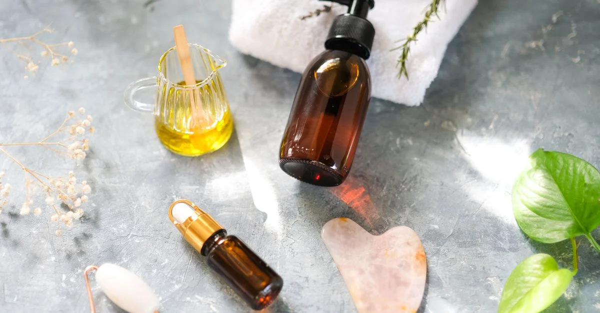 Composition à plat élégante présentant des produits de beauté avec des huiles, un rouleau en jade et des feuilles pour une routine de soins de la peau naturelle.