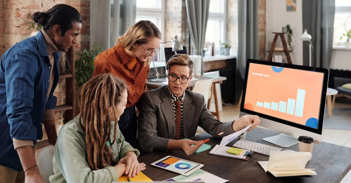 Un groupe de professionnels divers discutant des plans de marketing numérique dans un cadre de bureau moderne.
